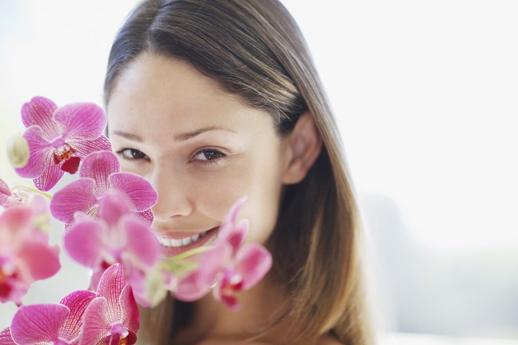 Bild des Gesichts einer Frau hinter einer Orchidee zur Darstellung von Gesichtsbehandlungen